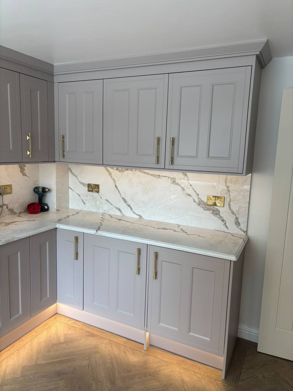 Fitted kitchen cabinetry with marble splashback and brass hardware