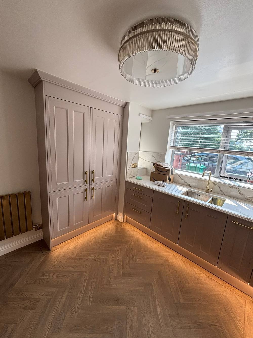 Fitted kitchen with tall cabinetry and herringbone flooring