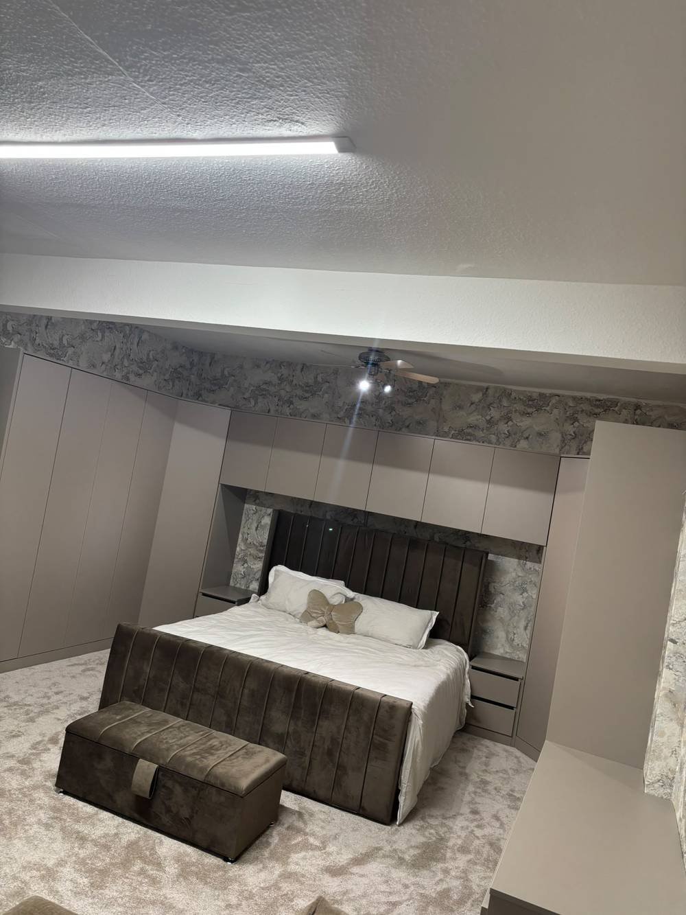 Fitted wardrobes and overbed cabinetry surrounding a bed