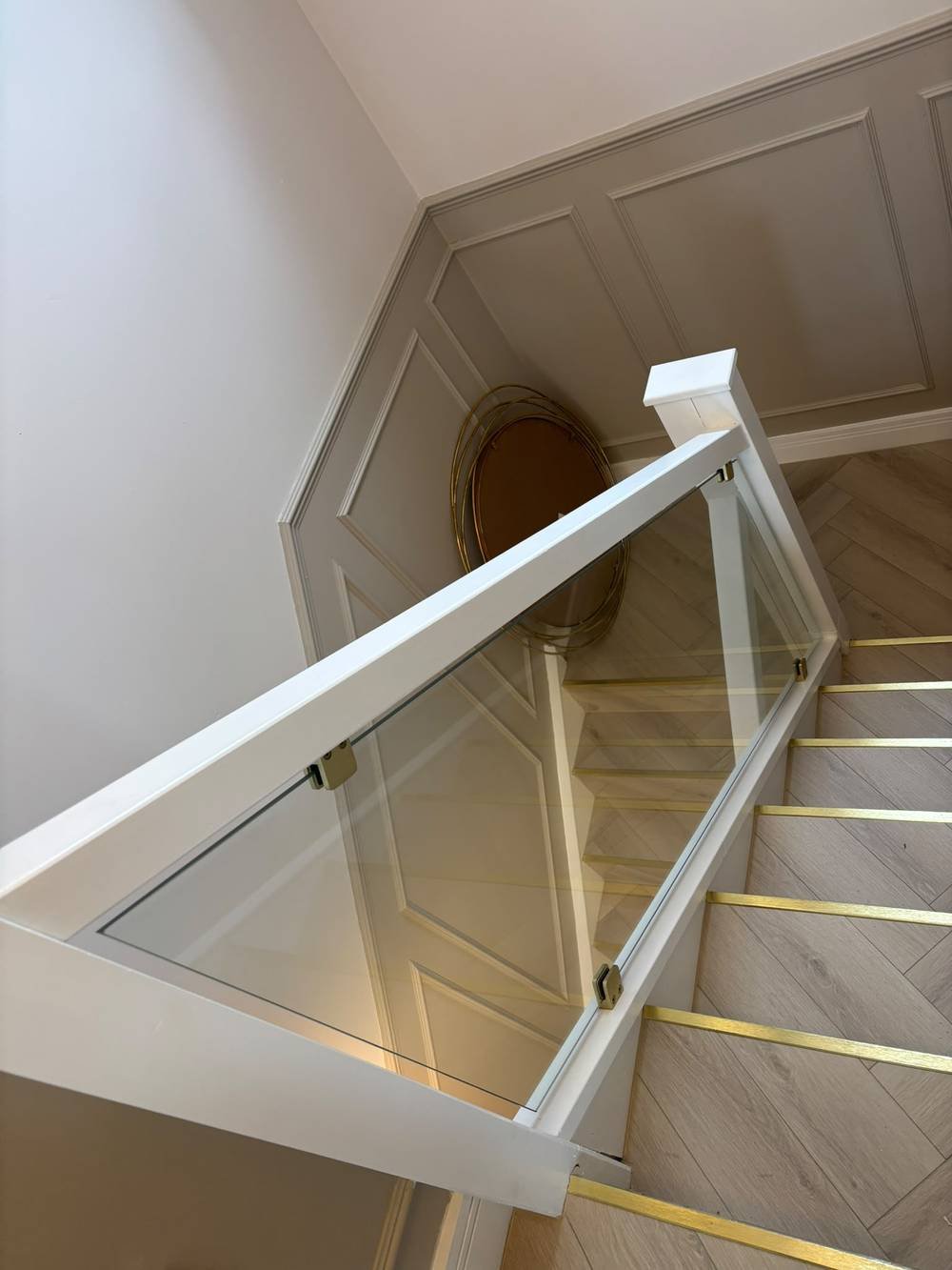 Glass balustrade with gold stair edging and herringbone flooring