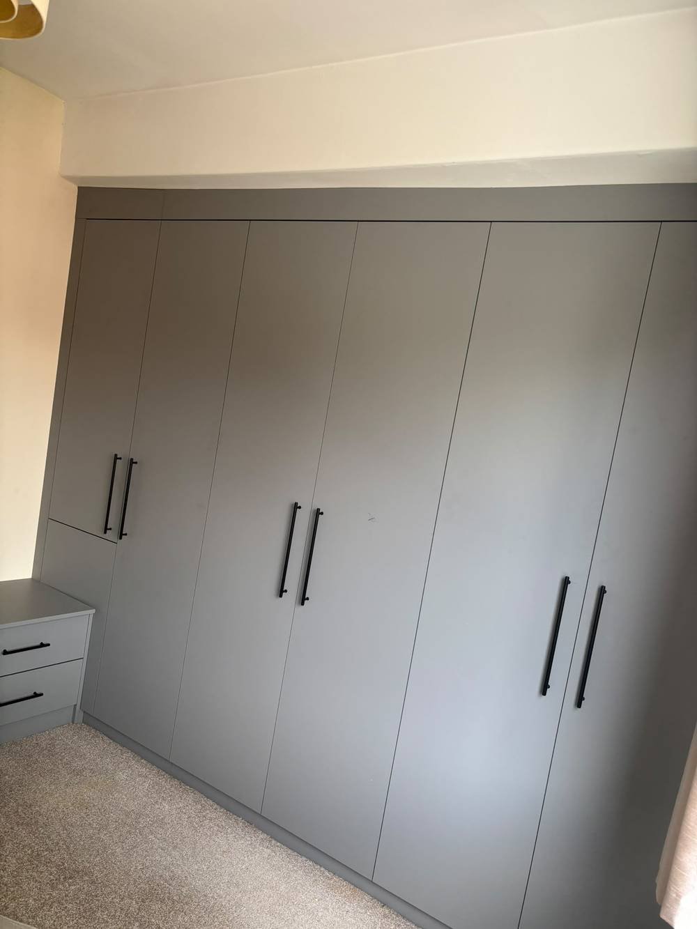 Grey fitted wardrobe wall with black handles