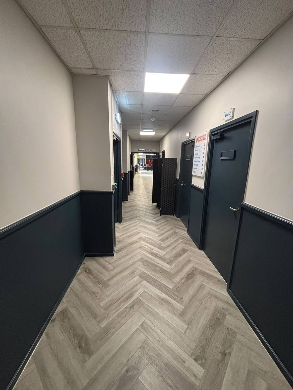 Herringbone flooring fitted along a hospitality corridor with private boxes
