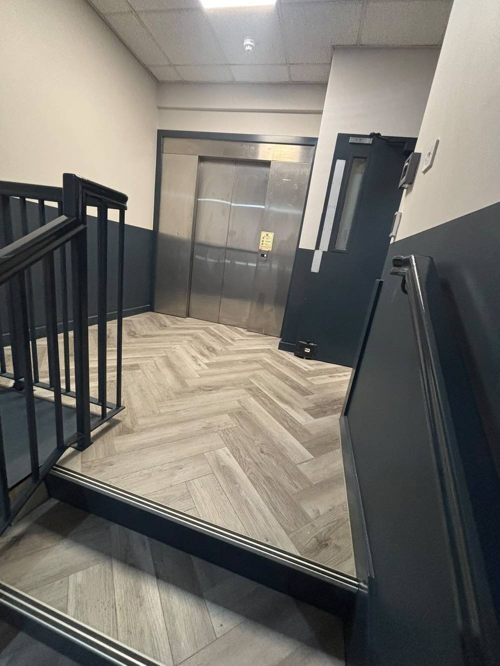 Herringbone flooring fitted around a stairwell and lift lobby