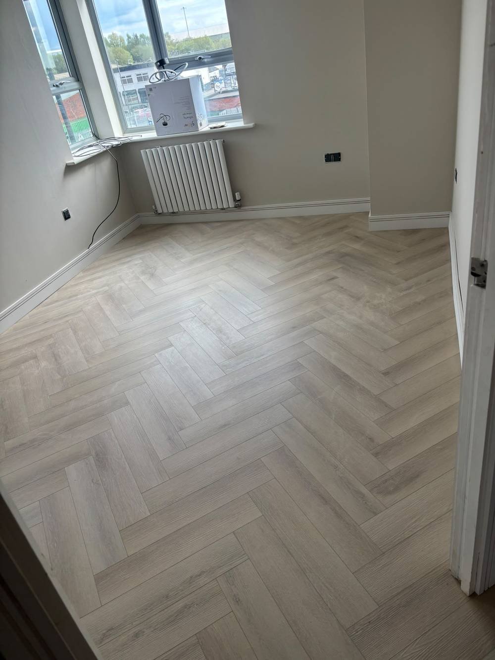 Herringbone flooring fitted in a bright corner room with bay window