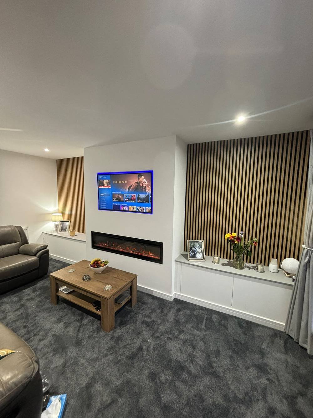 Media wall with LED-backlit TV recess and slatted panelling either side