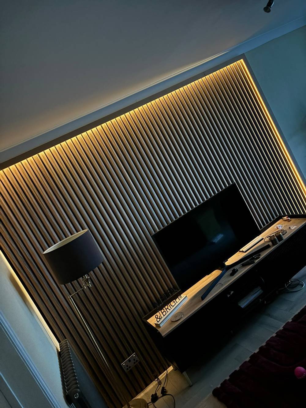 Slatted feature wall with floating TV shelf and warm lighting