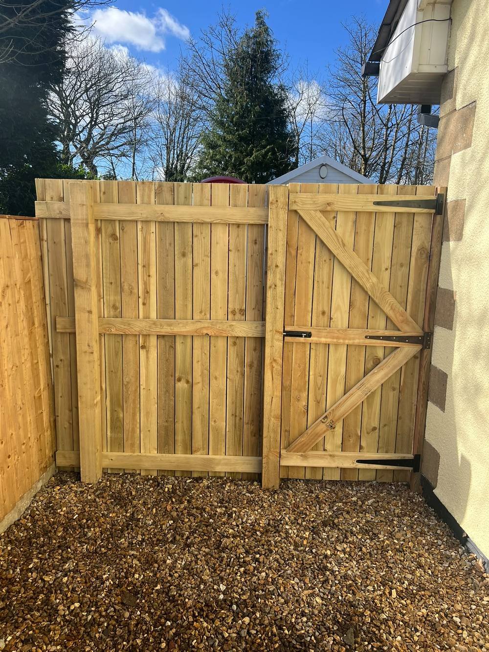 Timber fence panels and matching gate on a gravel base
